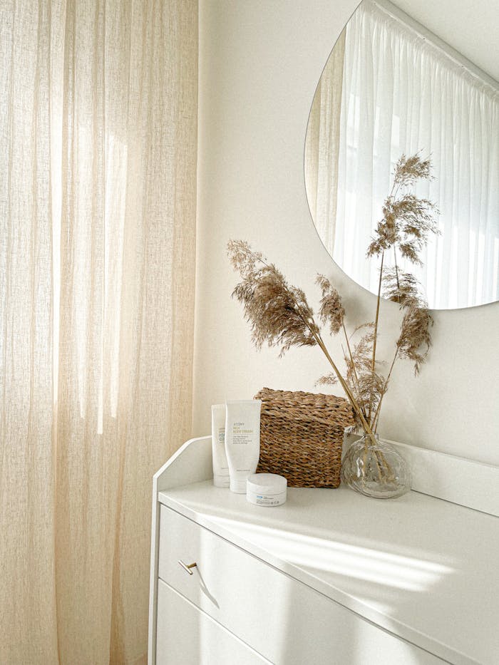 about-img Bright minimalist interior showing dresser, mirror, and dried plants, creating a serene atmosphere.