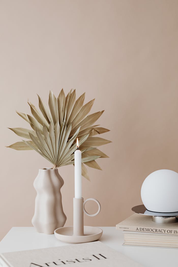 services-03 A minimalist arrangement featuring a vase with dry palm leaves and a candle.